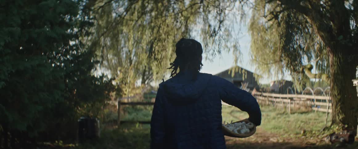 A woman holding a basket full of garlic walks towards a barn on the farm