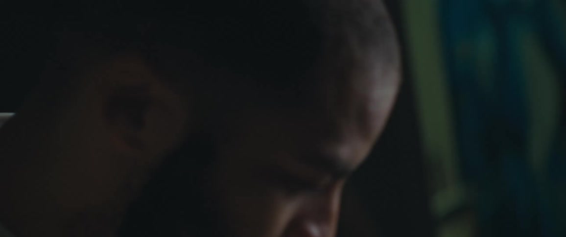 Closeup of a bearded man sitting in a dimly lit room looking at photos stored in a cardboard box