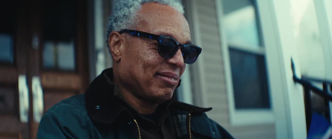 Elderly man is wearing sunglasses while sitting on his porch
