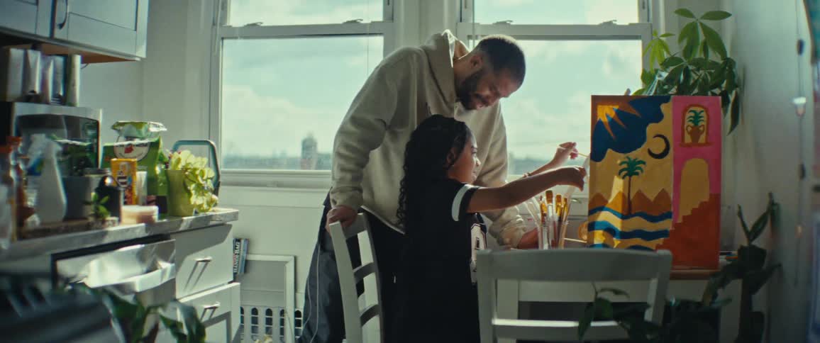 A father kisses his daughter on the forehead as she paints