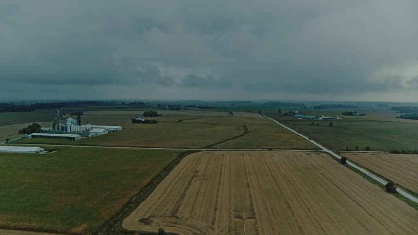 An aerial view of various plots of farmland under stormy skies