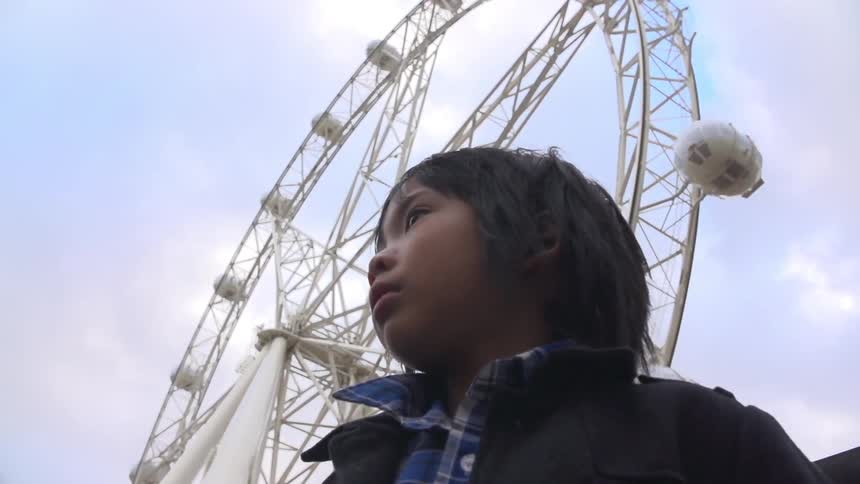 A kid in front of a ferris wheel