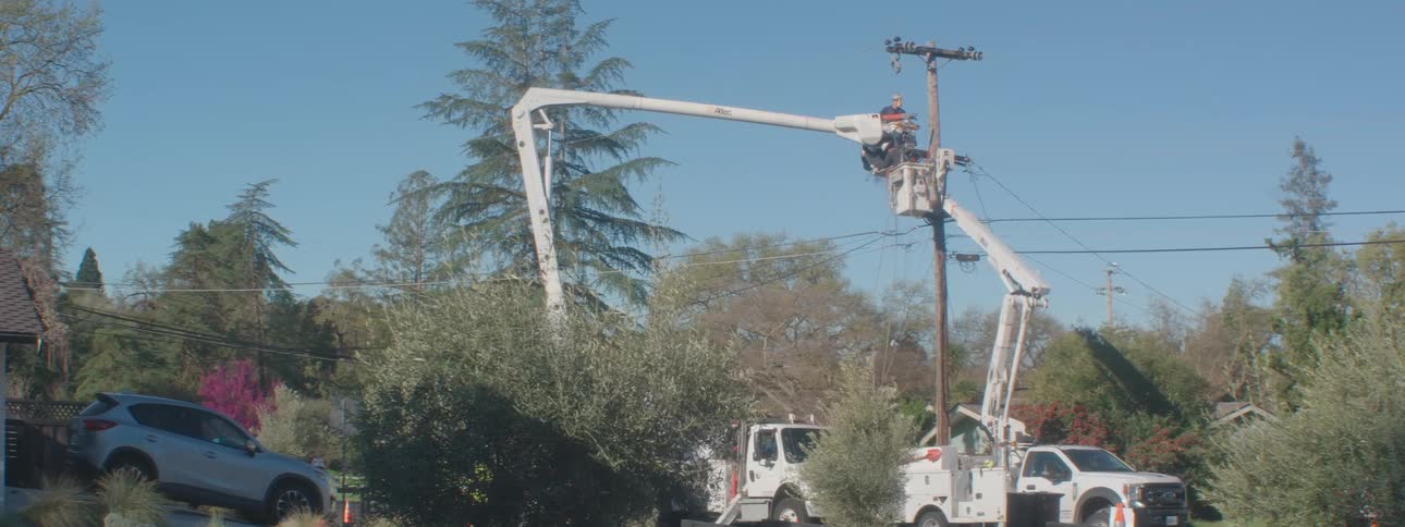 People on a crane performing maintenance on a pole
