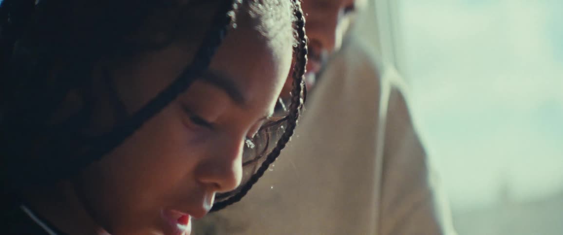 A father helps his daughter with a task in a sunlit room