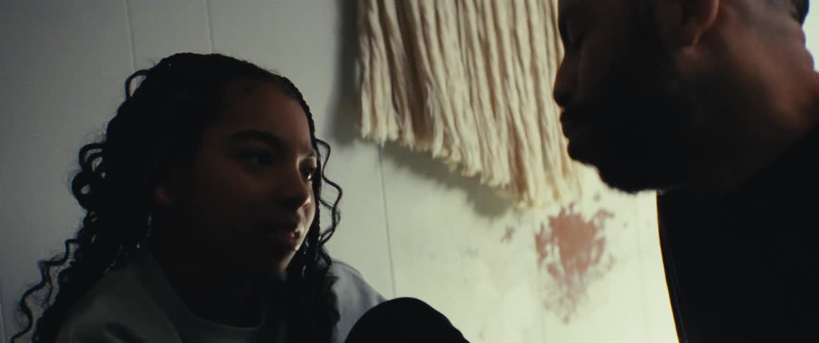 Father and daughter sit close to each other in a room talking