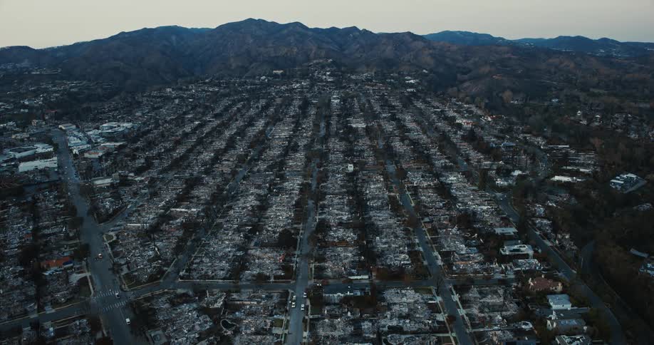 An aerial view of a neighborhood with extensive fire damage where multiple buildings have been reduced to rubble and charred remains