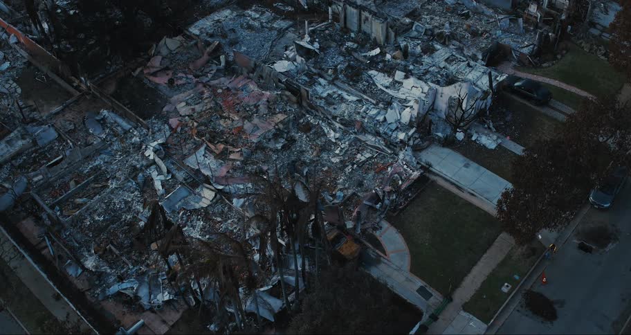 An aerial view of a neighborhood with extensive fire damage where multiple buildings have been reduced to rubble and charred remains