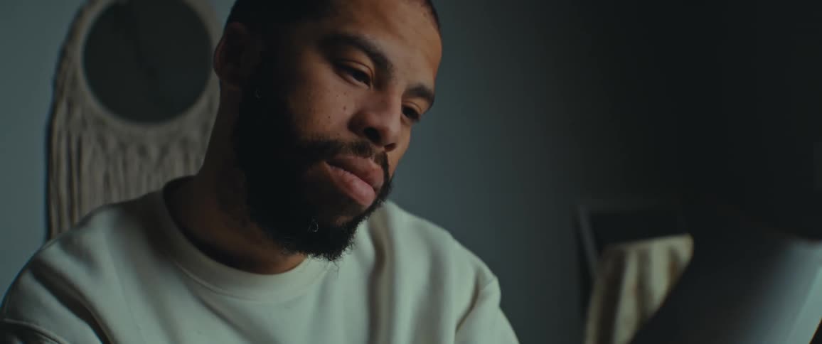 Closeup of a bearded man reading in a softly lit room