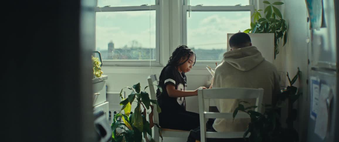 A father helps his daughter whit an arts project in a small sunlit kitchen