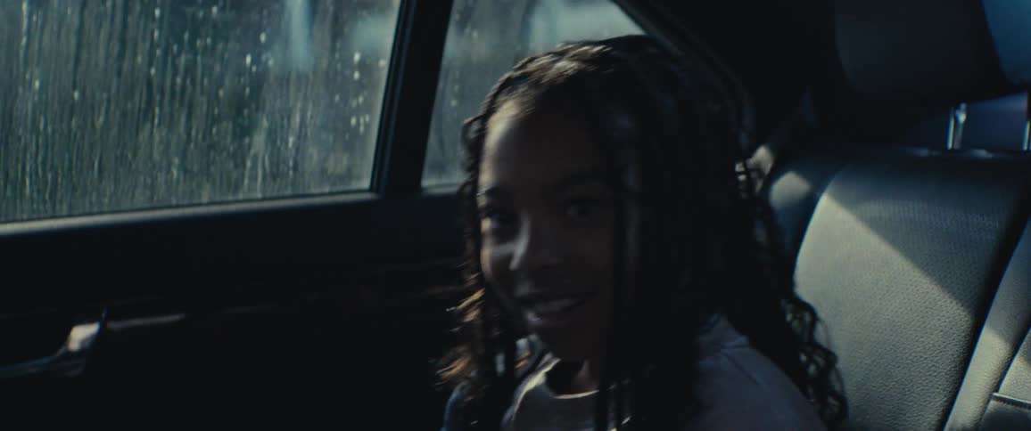 Closeup of a girl sitting in the backseat of a car playing and joking with someone in the front seat