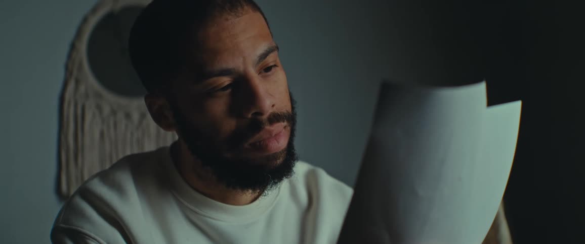 During the night time a man is reading a piece of paper