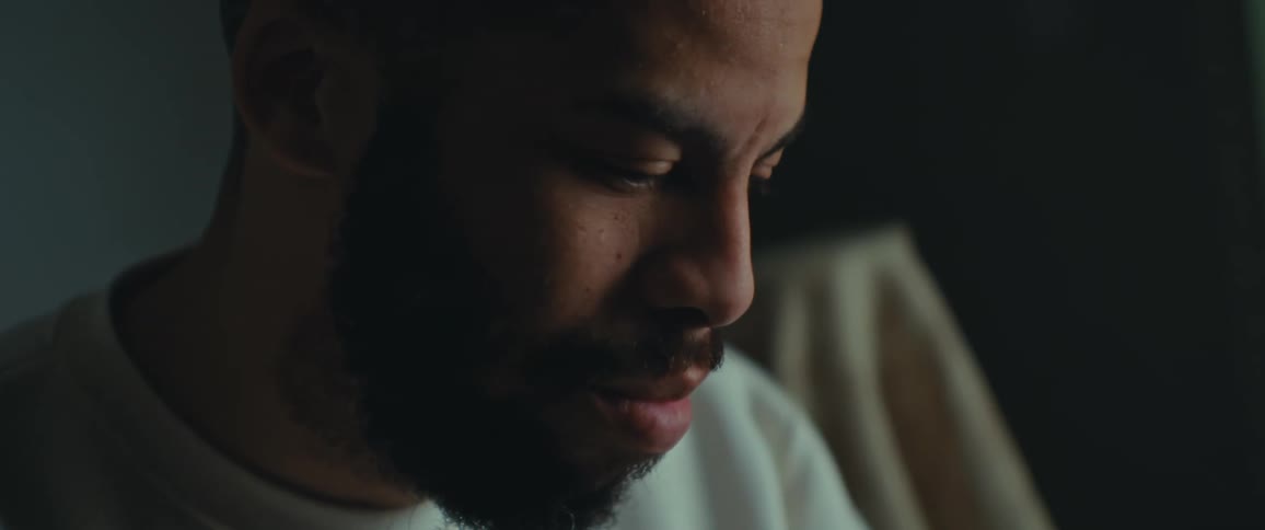 Close up of the face of a bearded man reading in a dimly lit room