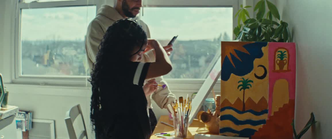 A father takes a photo of a painting a girl is working on