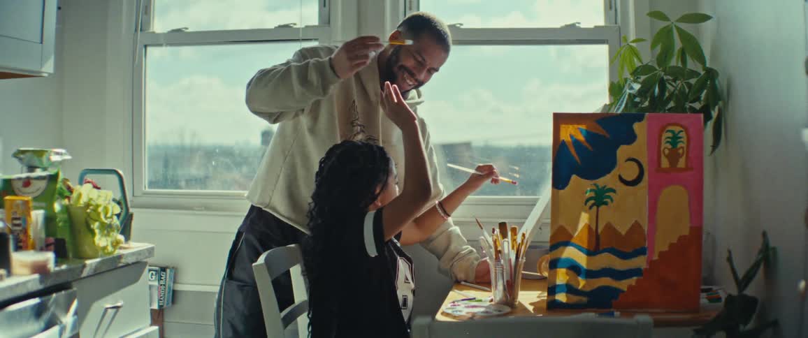 Father and daughter have fun painting together at a table lit by daylight