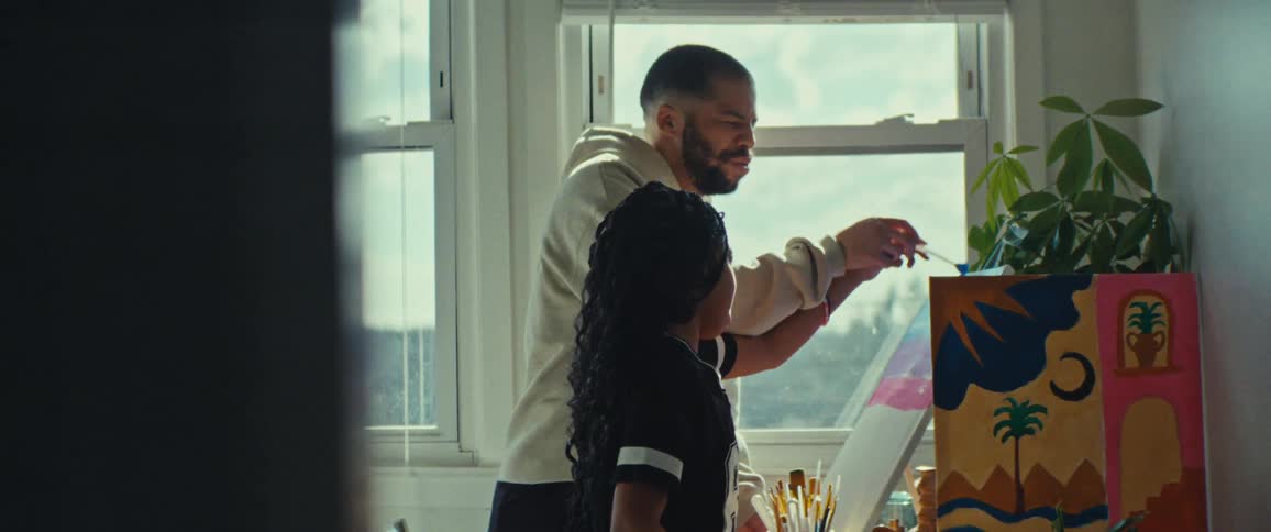 Father and daughter holding hands painting a picture