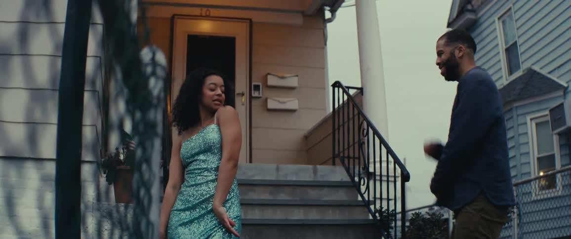 A father looks surprised when he sees his teenage daughter in a shiny blue dress and he hugs her on the front porch