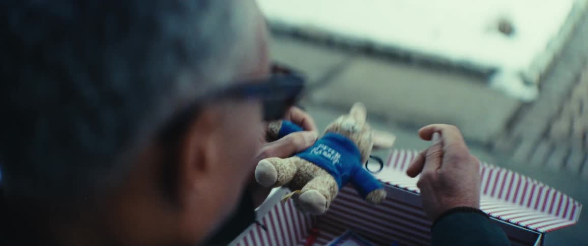 A person holds a stuffed rabbit toy and family photos from a cardboard box