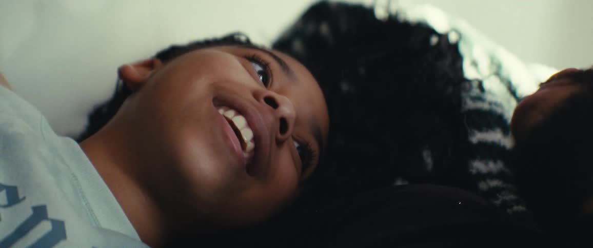 Child smiles while lying down while looking at someone next to him