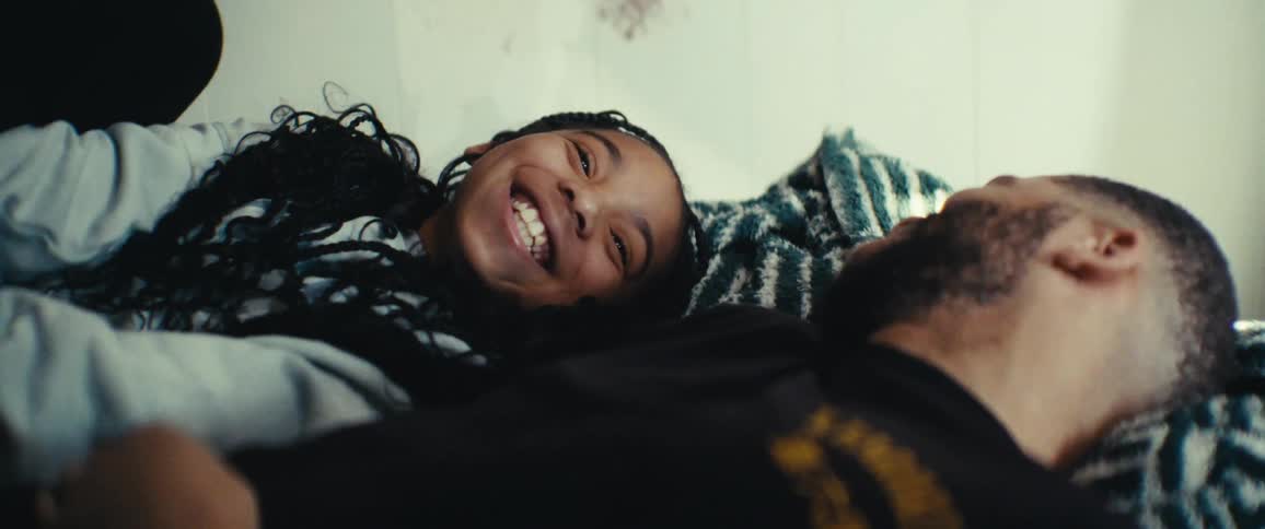 A father and daughter talk while laying in bed