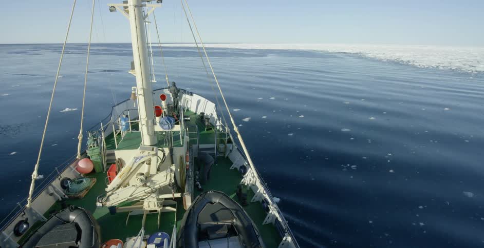 A boat floats on a body of water with snow and ice in the distance