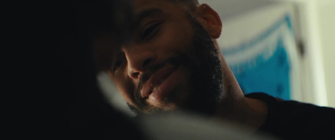 The face of a bearded man who is talking to someone in front of him with a subtle smile