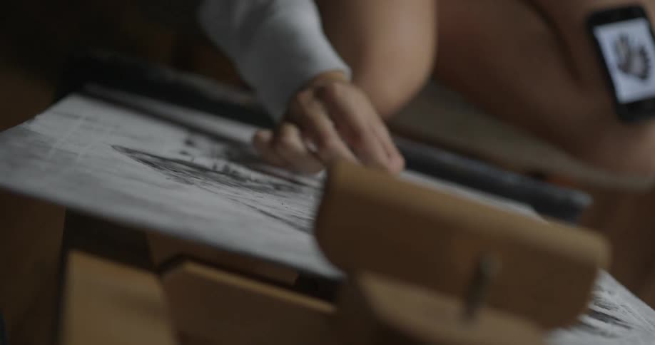 Person coloring with a dark object on a piece of paper