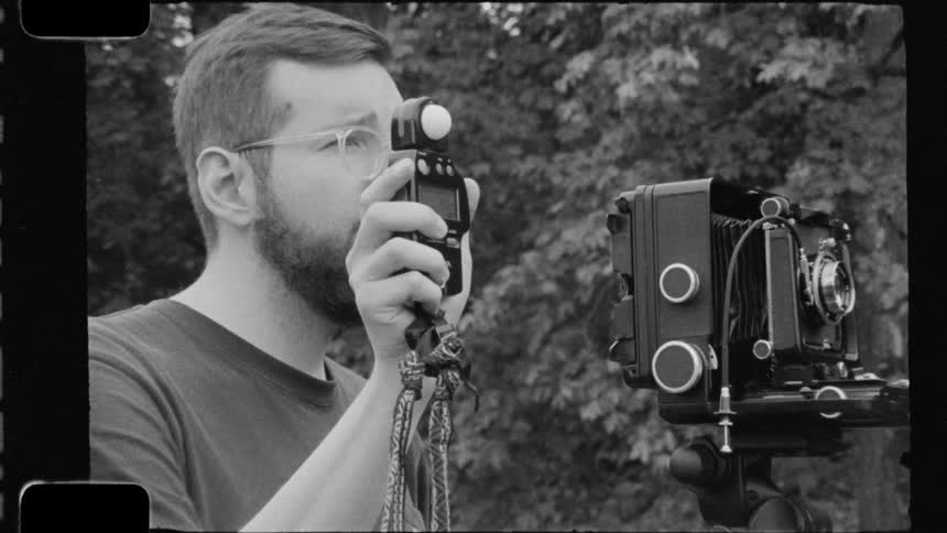 A photographer aims a camera and takes a photograph