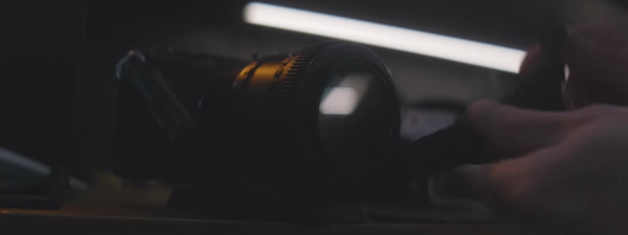 Camera sits on a shelf while i person is moving the cord