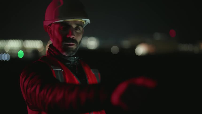 A construction worker is talking to someone during the night time