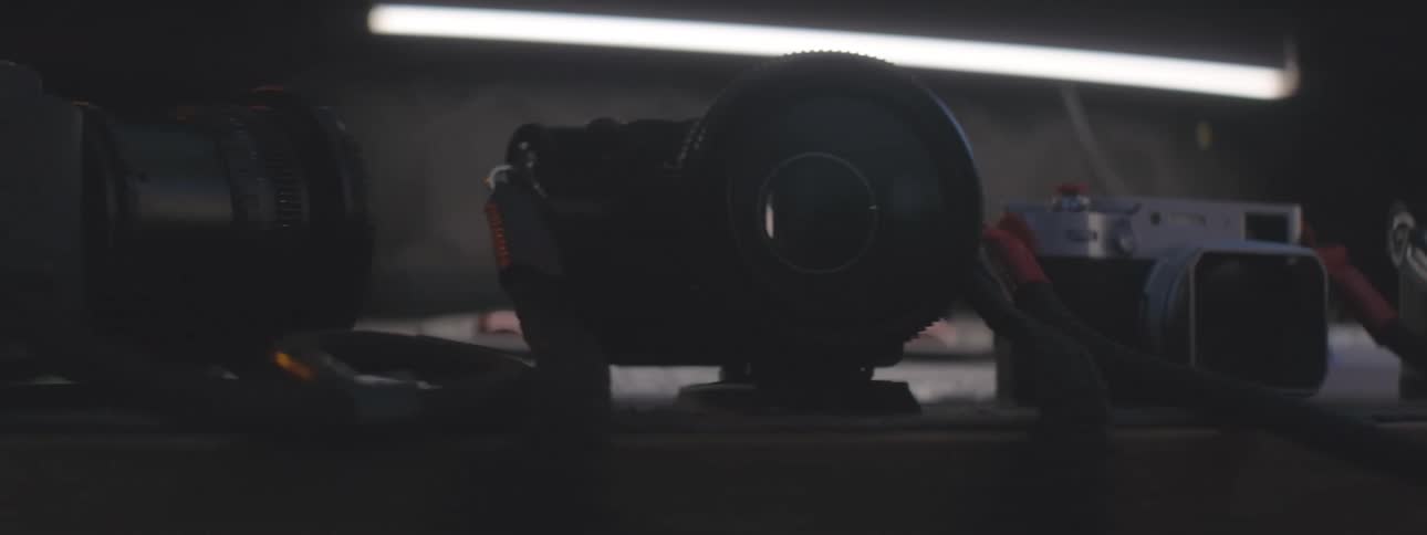 Cameras with red handles are lined up on a surface under soft lighting