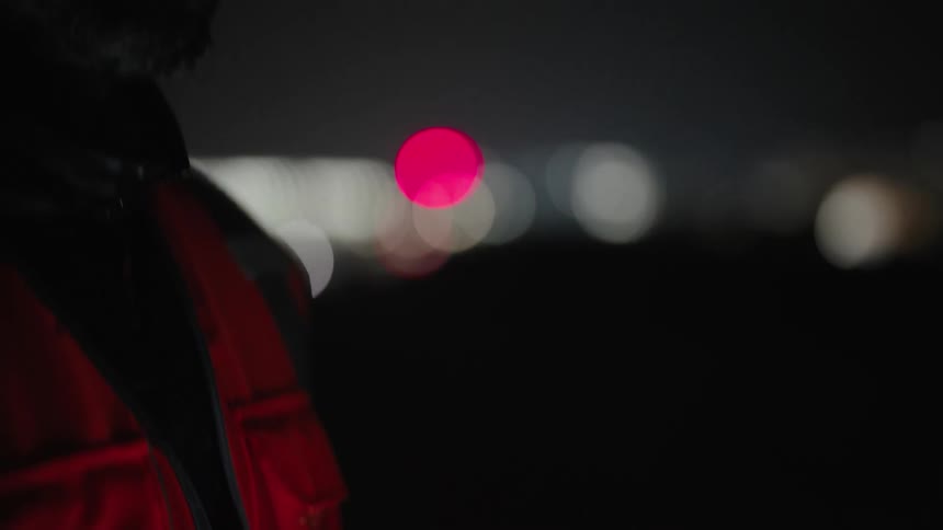 Man outdoors at night with protective helmet and vest interacting with a tablet