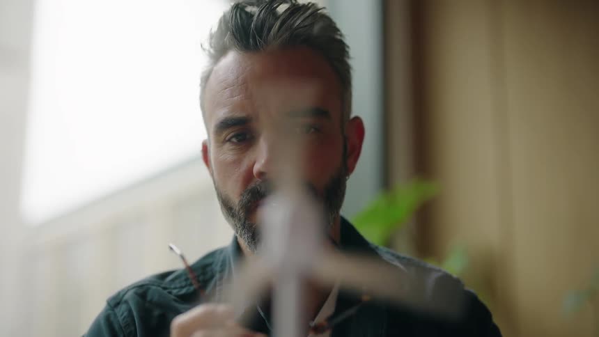 A man examines a model windmill and spins the blade