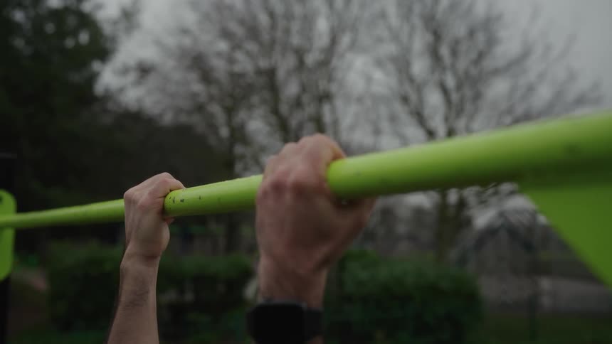 Determined man doing pullups outdoors