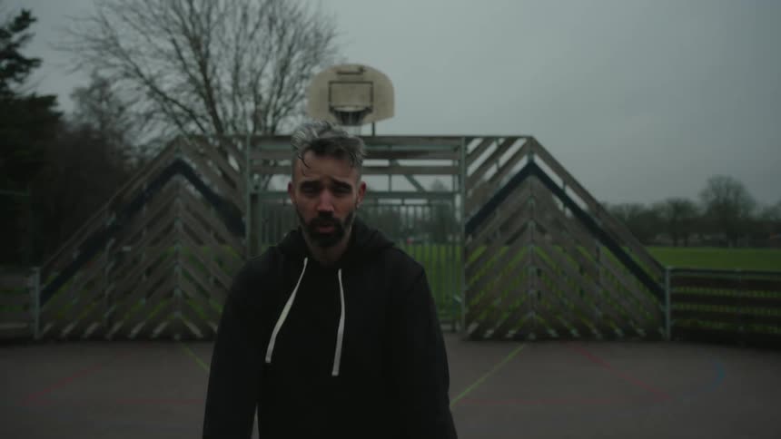 Man trains boxing on an outdoor court under a cloudy sky