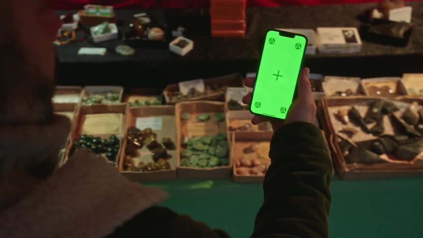 A man is filming rocks for sale at an outdoor market
