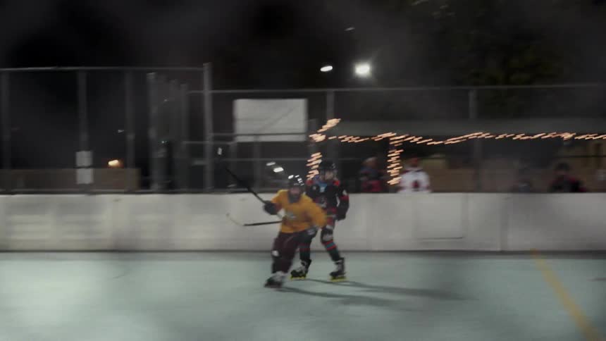 Hockey players play a game on a court at night