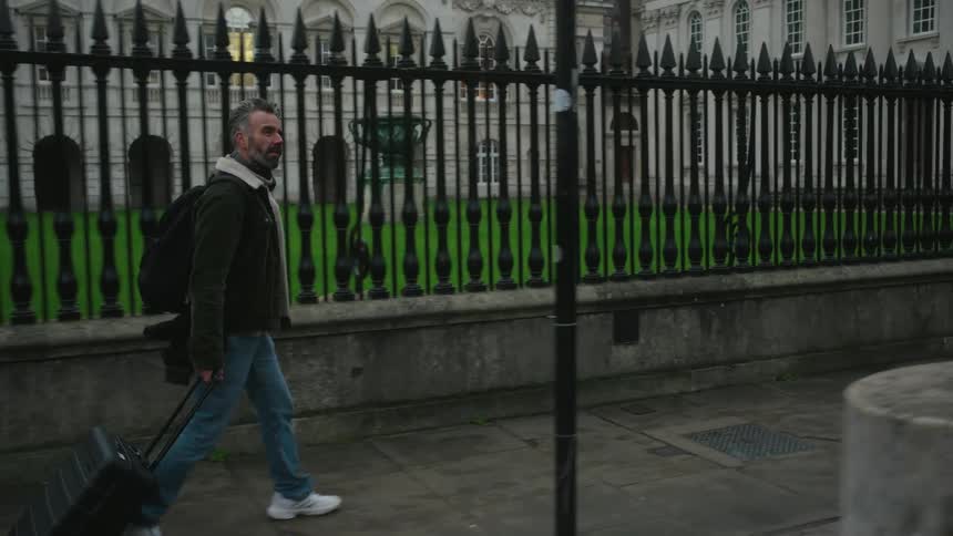 Man walking with a suitcase on the sidewalks of a classic city