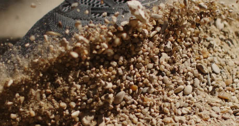 Shoes raise a wave of pebbles and dust when they touch dry ground