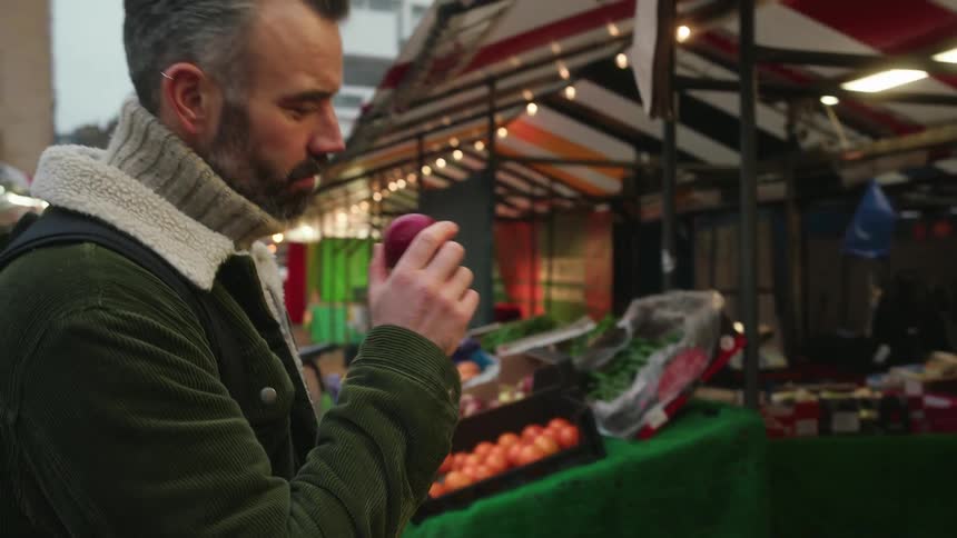 A man is browsing the produce at the outdoor market