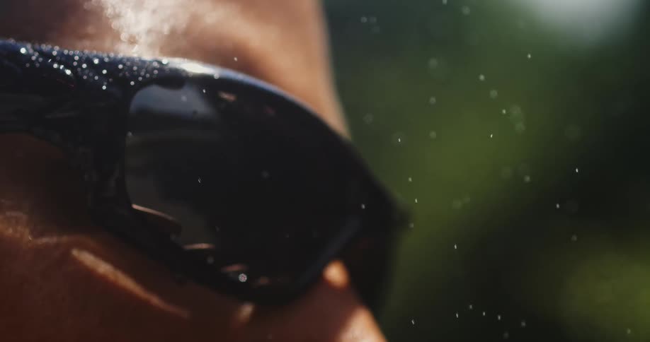Rain falling on the face of a person wearing dark sunglasses