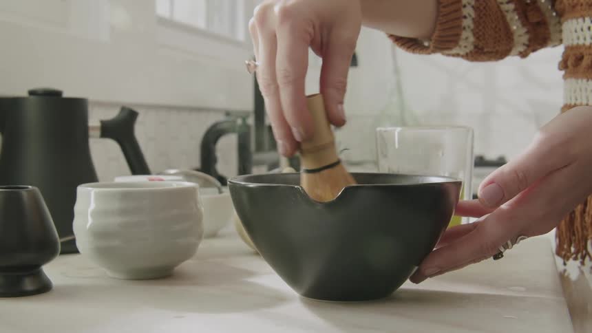 A woman is using a small whisk in the bowl