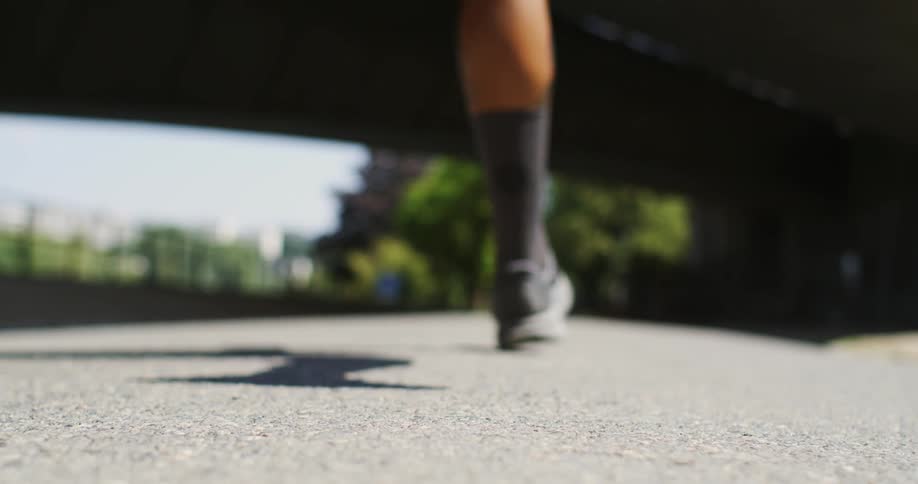 Lowangle shot of a persons shoes running on a street towards an underpass