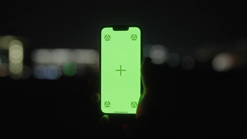 A person is holding a cell phone at night
