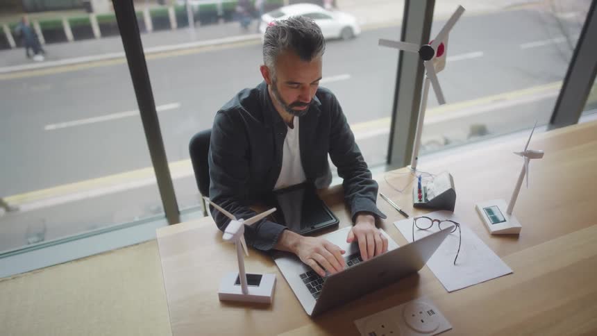 Man sitting at an office desk typing on a laptop