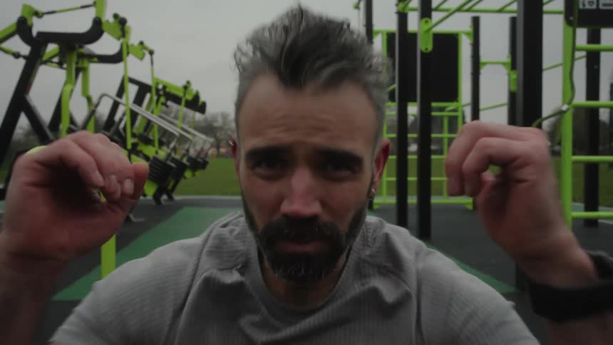 A man performs abdominal crunches at an outdoor gym under a cloudy sky