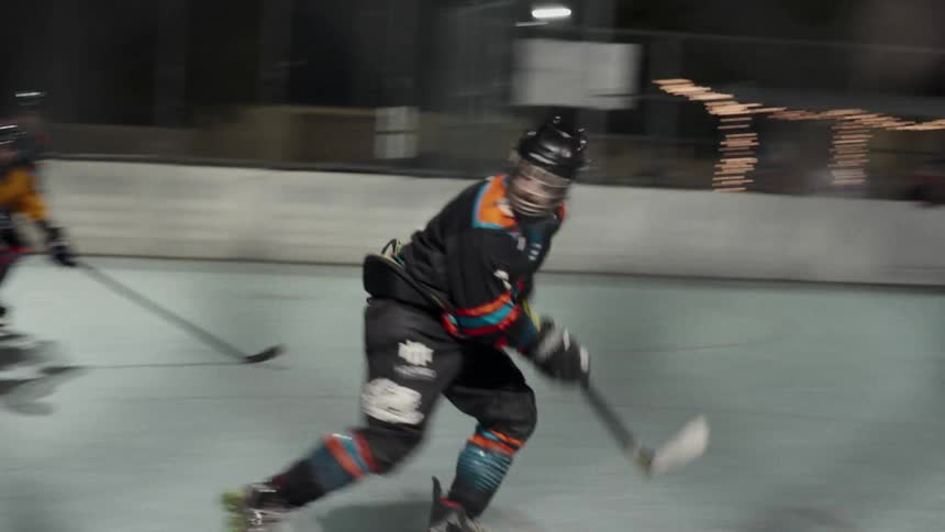 Some people playing ice hockey and running with sticks in their hands on an ice rink