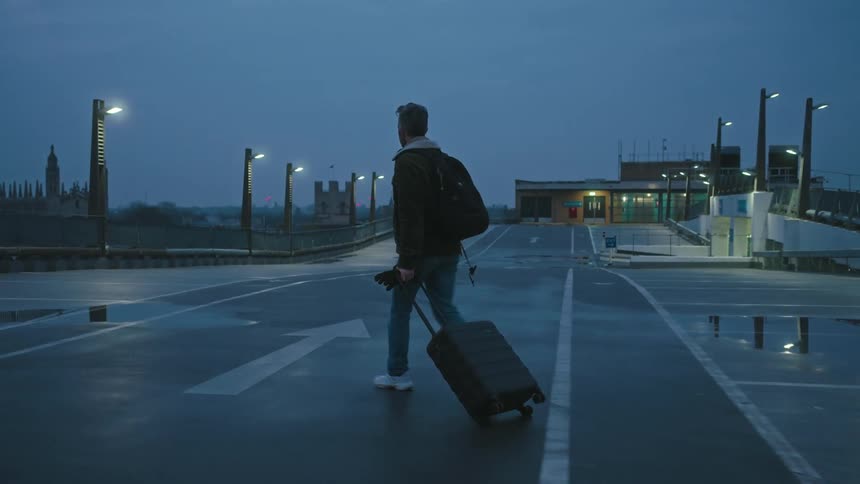 A man drags his luggage across the road