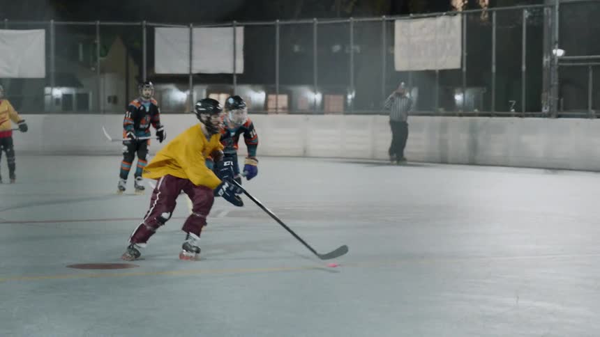 Hockey players play a game on an outdoor court at night