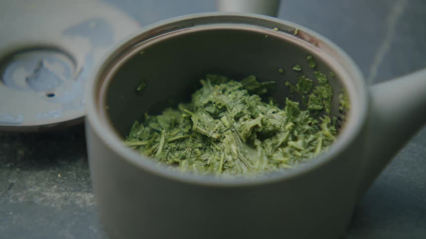 Close up of japanese green tea stems filling a ceramic tea pot