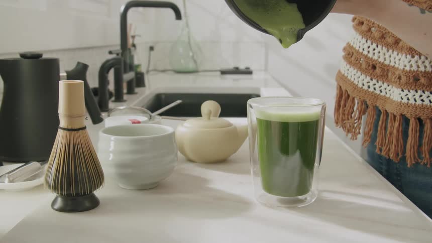 Green juice being poured into a glass cup